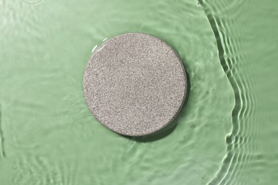 Photo of Presentation for product. Stone podium in water on green background, top view