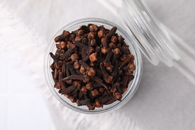 Photo of Aromatic cloves in glass jar on white table, top view