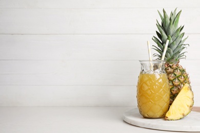 Photo of Freshly made pineapple juice on white table. Space for text