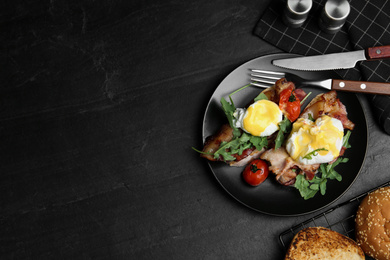 Photo of Delicious eggs Benedict served on black table, flat lay. Space for text