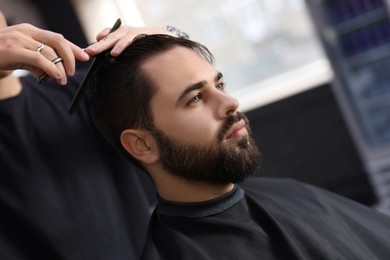 Photo of Professional hairdresser working with client in barbershop