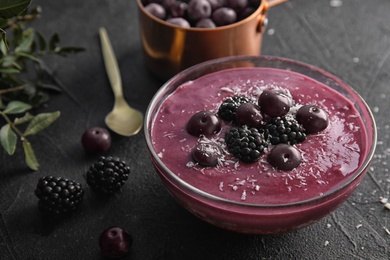 Photo of Bowl of tasty acai smoothie on dark table