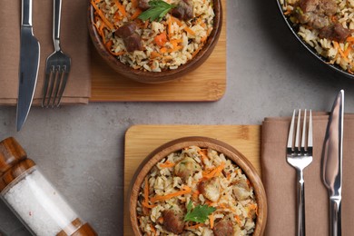 Photo of Delicious pilaf with meat and carrot served on grey textured table, flat lay