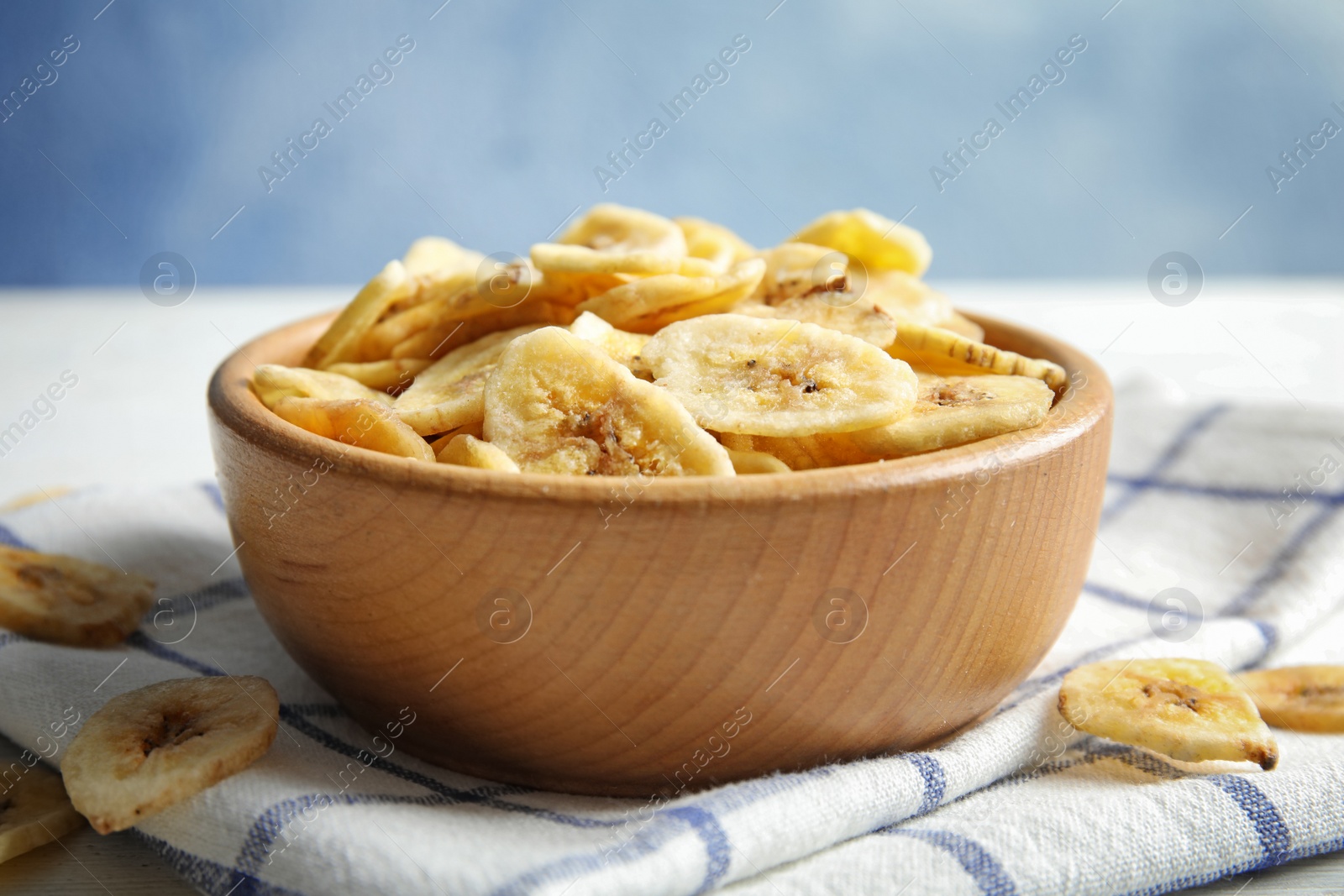 Photo of Wooden bowl with sweet banana slices on table. Dried fruit as healthy snack