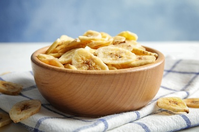 Wooden bowl with sweet banana slices on table. Dried fruit as healthy snack