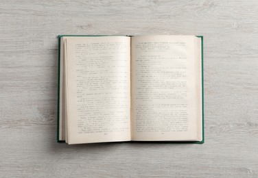 Open hardcover book on white wooden table, top view