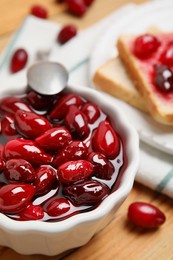 Photo of Delicious dogwood jam with berries in bowl on table, closeup