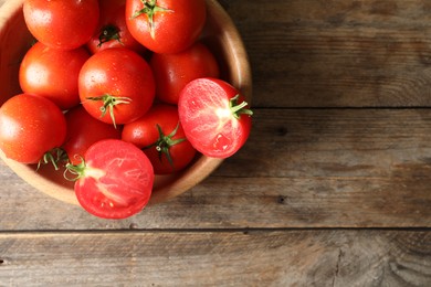 Fresh ripe tomatoes in bowl on wooden table, top view. Space for text