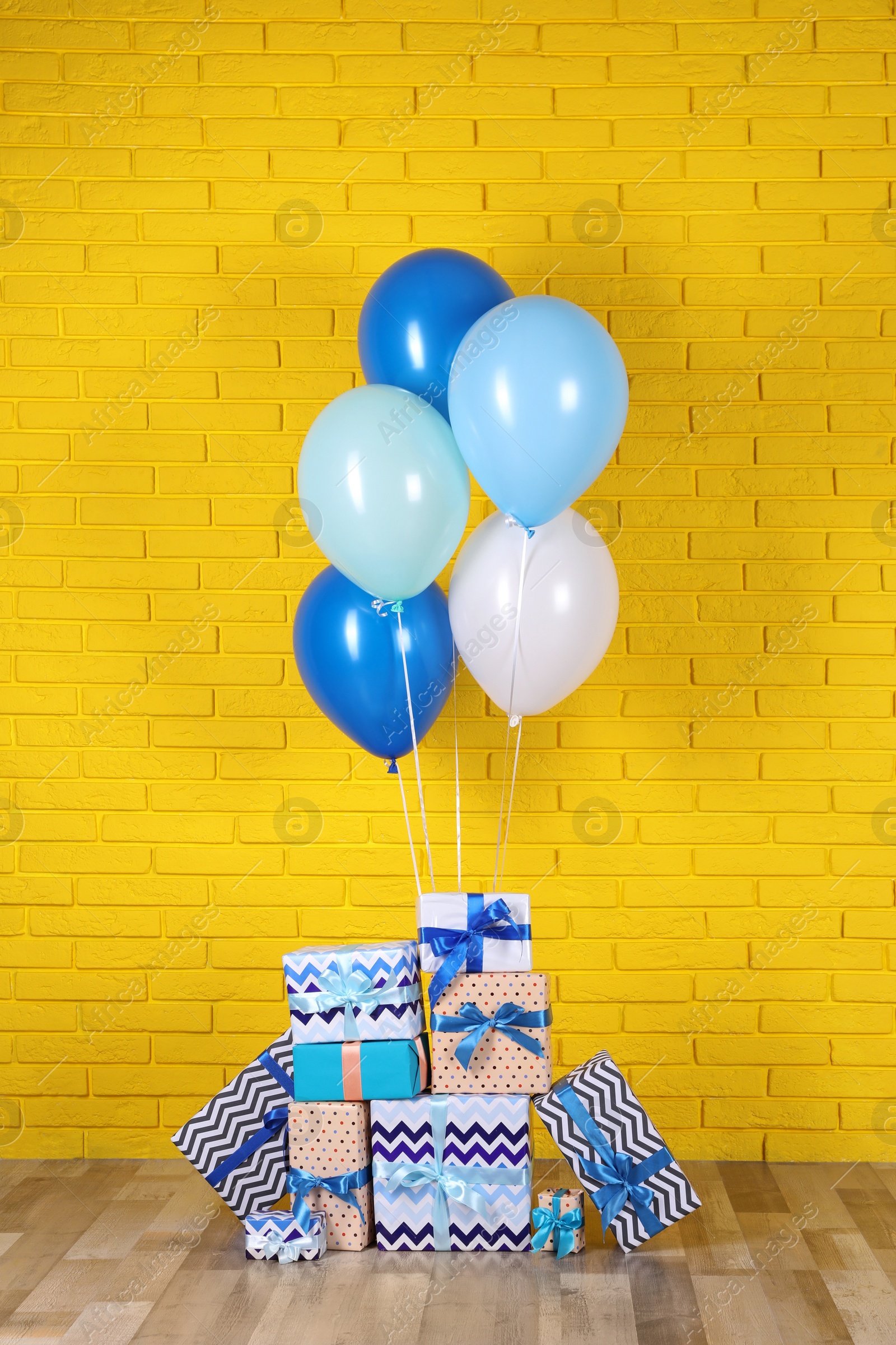 Photo of Many gift boxes and balloons near yellow brick wall