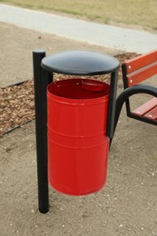 Photo of Red metal trash bin on city park