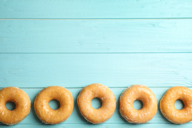 Delicious donuts on light blue table, top view. Space for text
