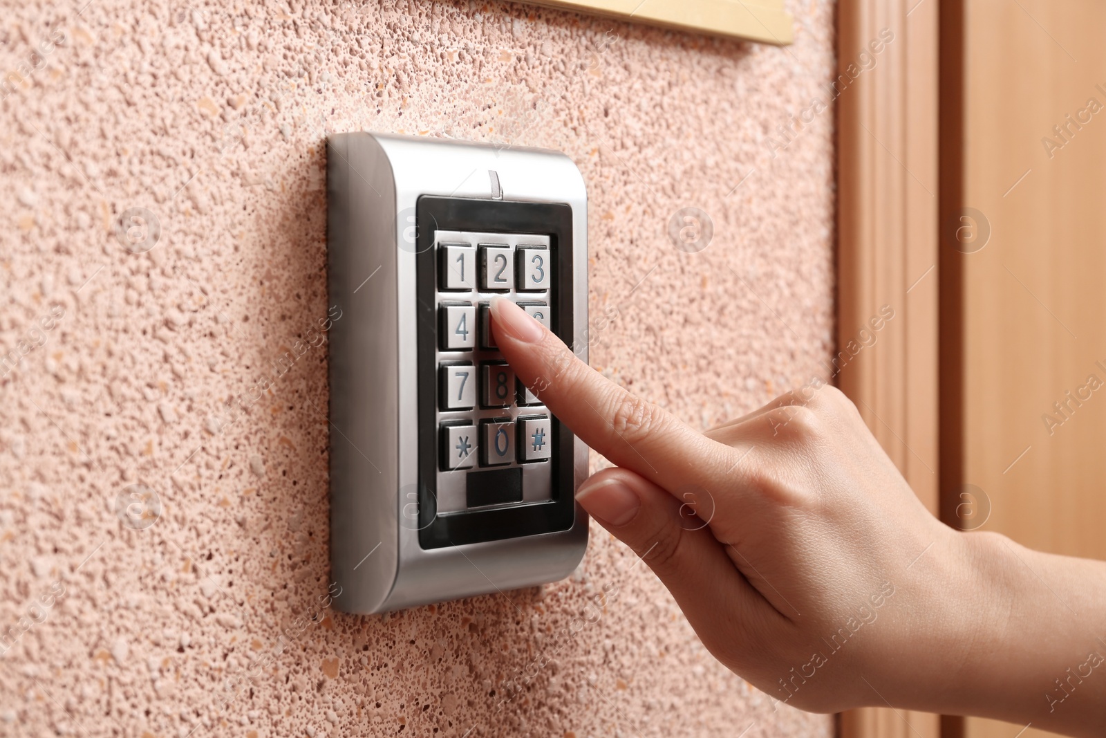 Photo of Woman entering code on electronic lock's keypad indoors, closeup