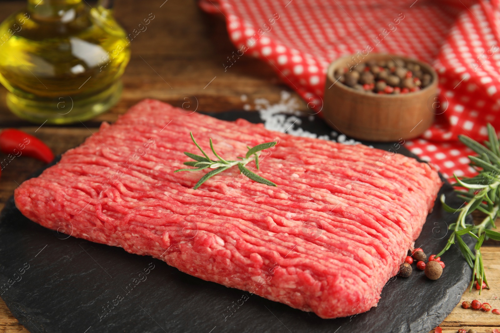 Photo of Raw fresh minced meat and other ingredients on wooden table, closeup