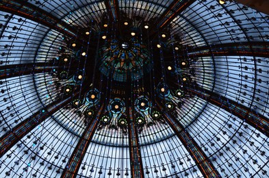 Paris, France - December 10, 2022: Beautiful stained glass dome and Christmas decor in Galeries Lafayette Haussmann, low angle view