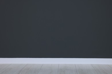 Photo of Beautiful dark grey wall and wooden floor in clean empty room