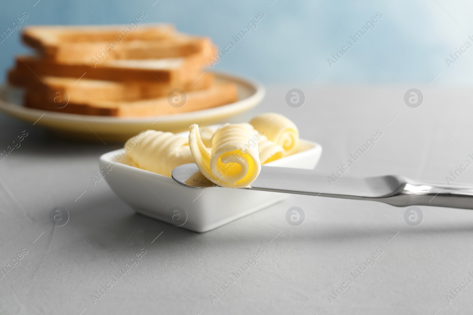 Photo of Knife and gravy boat with butter curls on table