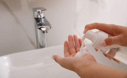 Photo of Teenage girl using cleansing foam in bathroom, closeup. Skin care cosmetic