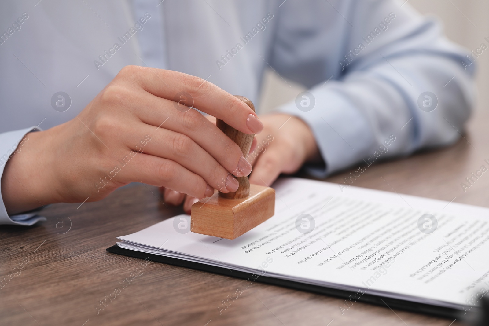 Photo of Woman stamping document at wooden table, closeup