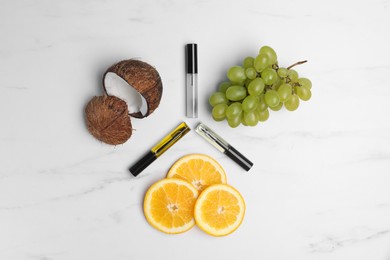 Flat lay composition with different eyelash oils and fresh fruits on white marble table