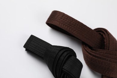 Brown and black karate belts on white background, flat lay