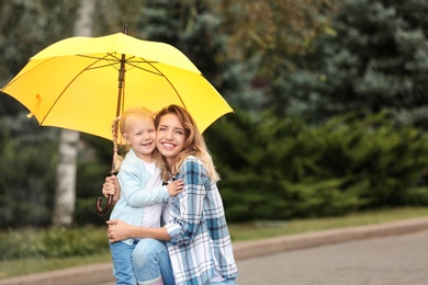 Happy mother and daughter with umbrella in park