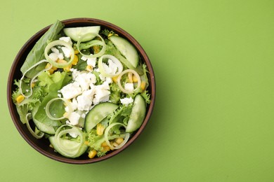 Bowl of tasty salad with leek and cheese on green table, top view. Space for text