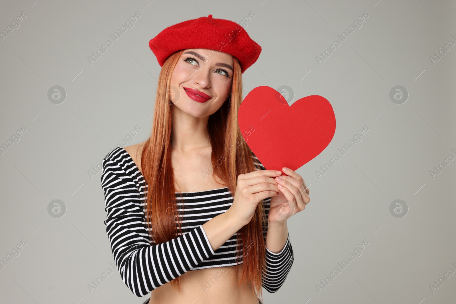 Photo of Young woman with paper heart on light grey background