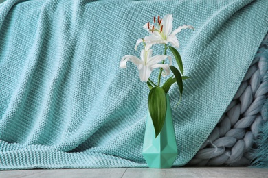 Vase with beautiful lilies and mint cloth on background