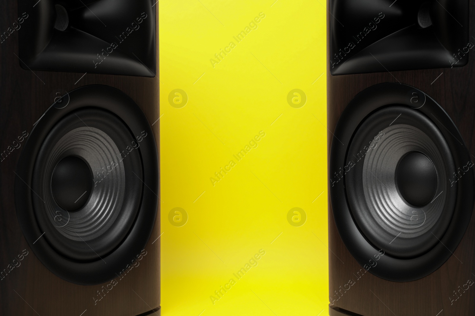 Photo of Wooden sound speakers on yellow background, closeup. Space for text