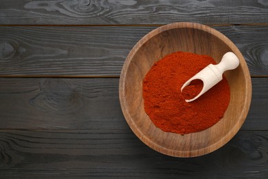 Photo of Bowl of aromatic paprika on black wooden table, top view. Space for text