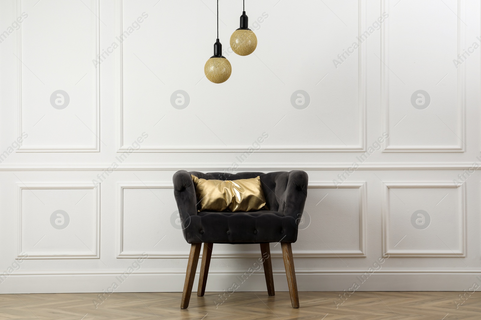 Photo of Stylish armchair with cushion near white wall indoors. Interior design