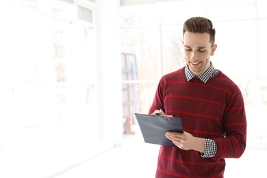 Male real estate agent with clipboard indoors