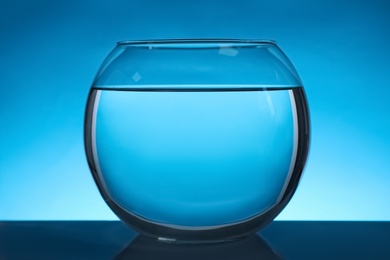 Photo of Round fish bowl filled with water on blue background