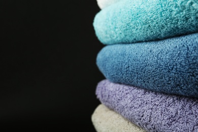 Photo of Different fresh soft terry towels on dark background, closeup. Space for text