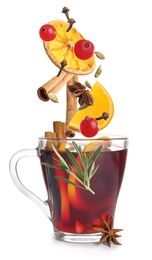Cut orange, cranberries and different spices falling into glass cup of mulled wine on white background 