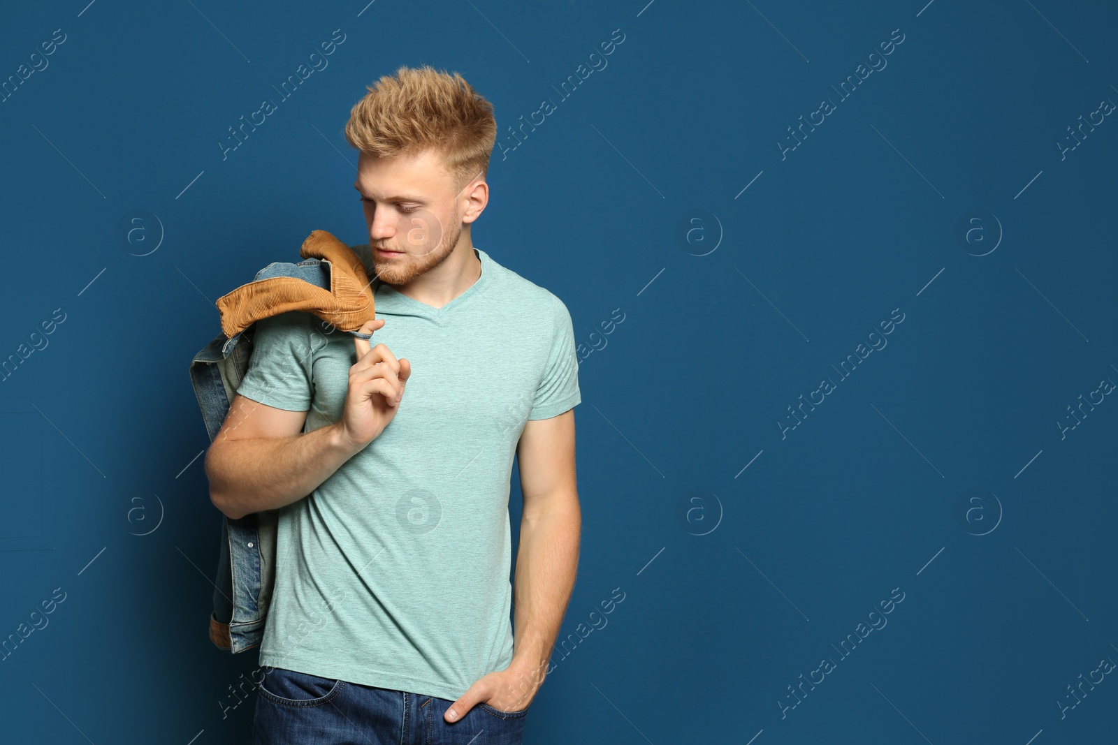 Photo of Young man wearing blank t-shirt on blue background. Mockup for design