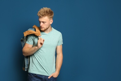 Young man wearing blank t-shirt on blue background. Mockup for design