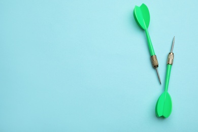 Photo of Green dart arrows on blue background, flat lay with space for text