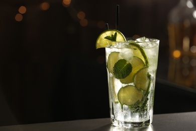 Glass of fresh alcoholic cocktail on bar counter, space for text