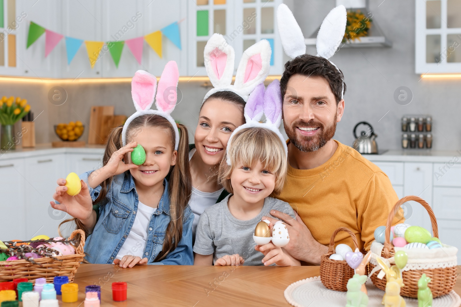 Photo of Happy family with Easter eggs at table in kitchen