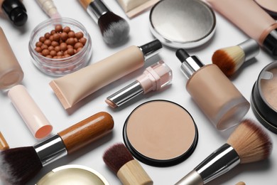 Photo of Face powders and other makeup products on white background, closeup