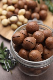 Photo of Tasty Macadamia nuts in jar on table, closeup