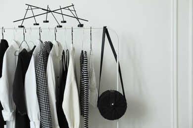 Photo of Rack with stylish clothes near white wall