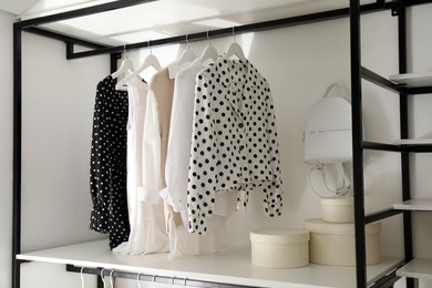 Photo of Storage rack with stylish women's clothes and accessories indoors