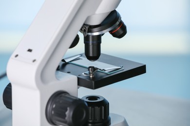 Photo of Modern microscope on light blue background, closeup. Medical equipment