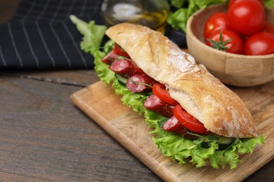 Photo of Delicious sandwich with sausages and vegetables on wooden table, closeup. Space for text