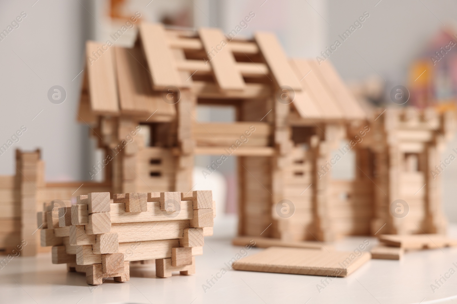 Photo of Wooden entry gate and building blocks on white table indoors, selective focus. Children's toy