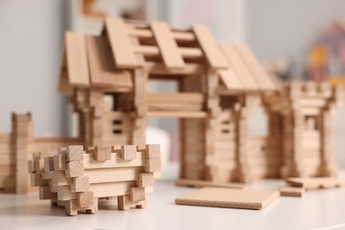 Wooden entry gate and building blocks on white table indoors, selective focus. Children's toy