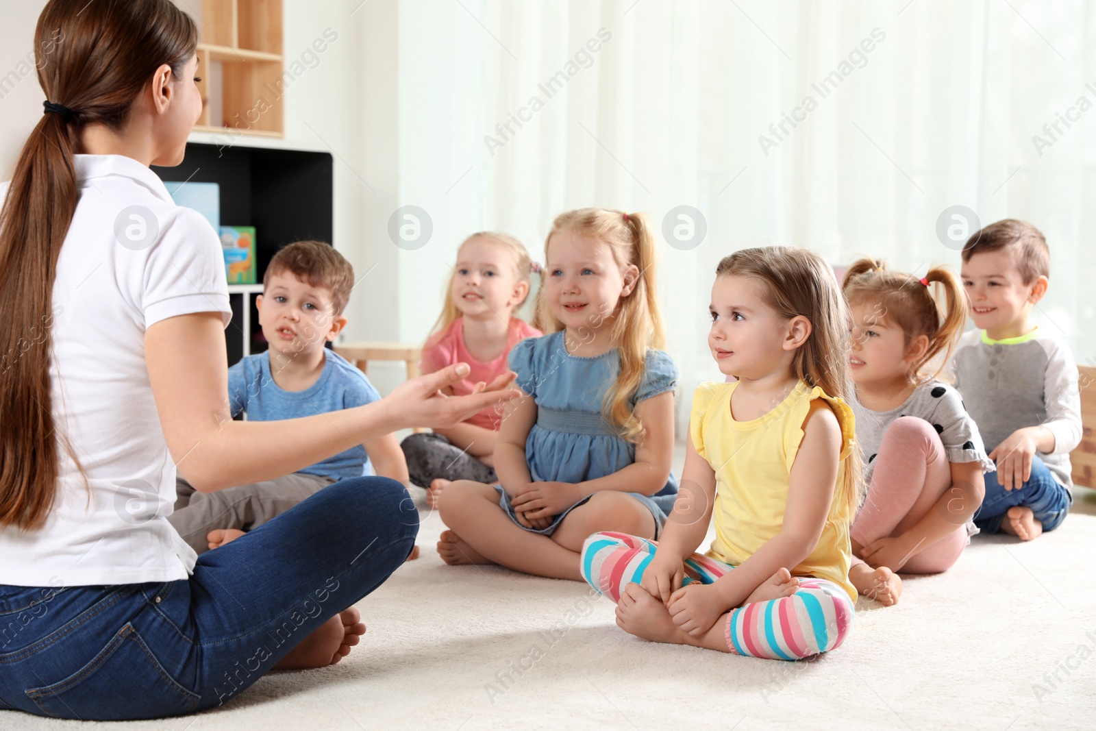 Photo of Kindergarten teacher and little children indoors. Learning and playing