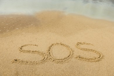 Message SOS drawn on sand near sea